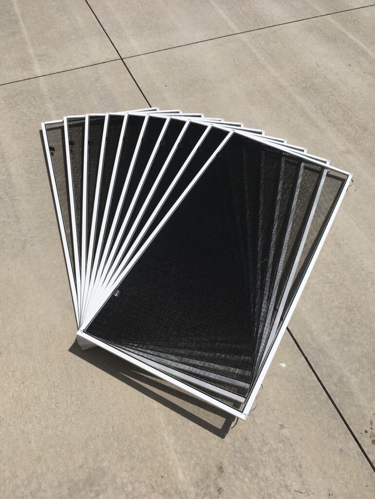 Pile of Window Screens lying on the ground before being installed.