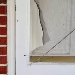Torn screen door needing repair or replacement.